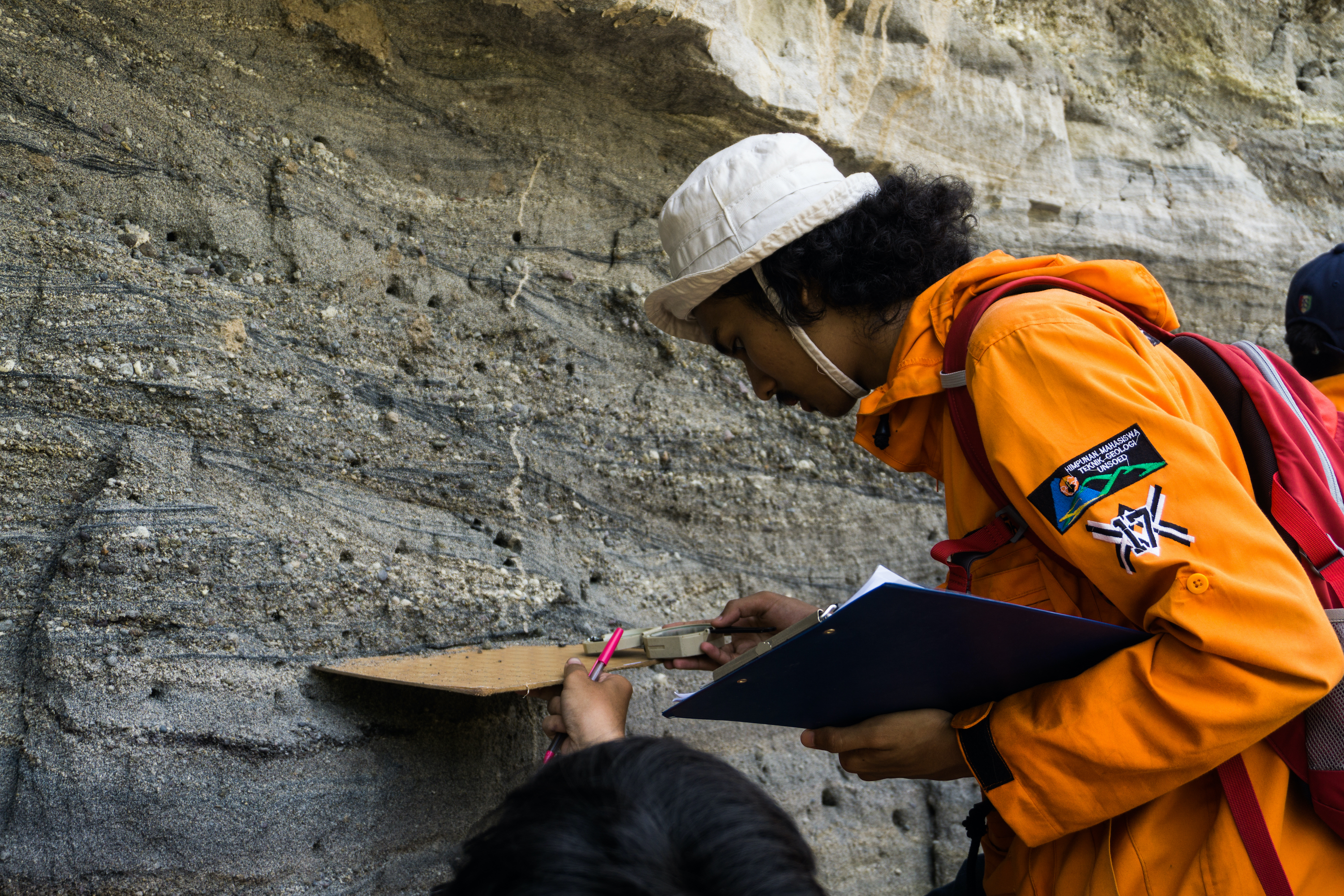 一个地质工程专业的学生测量砂岩，凝灰岩层古水流。“>
           <div class=