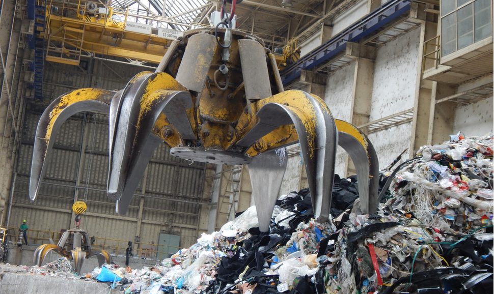 在一个废物转化能源的工厂里，一个巨大的金属爪运输混合废物