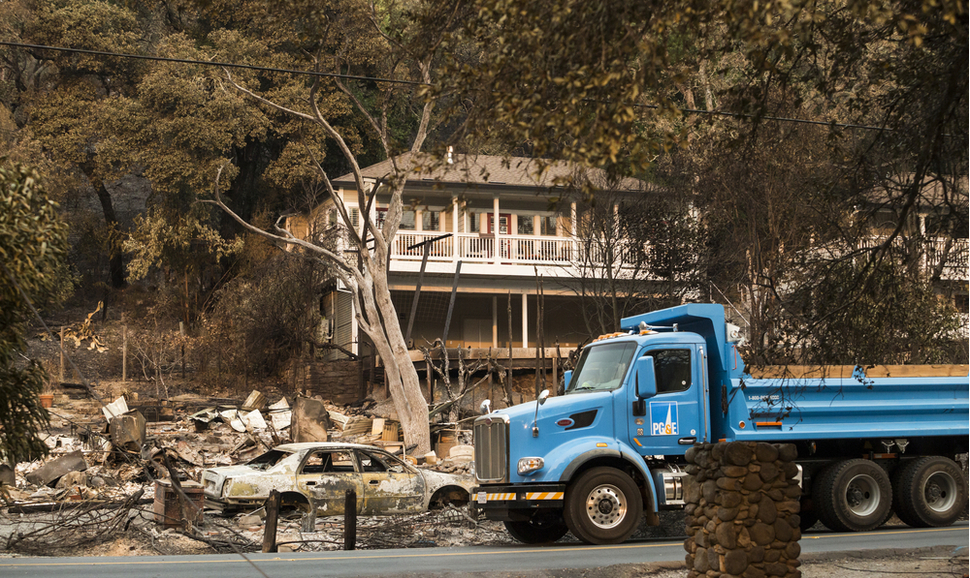 A PG&E truck drives through a Sonoma County, California, neighborhood devastated by fires 一辆太平洋煤气与电力公司的卡车驶过加利福尼亚州索诺玛县的一个被大火摧毁的社区