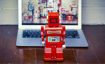 红色玩具机器人看着打开的笔记本电脑