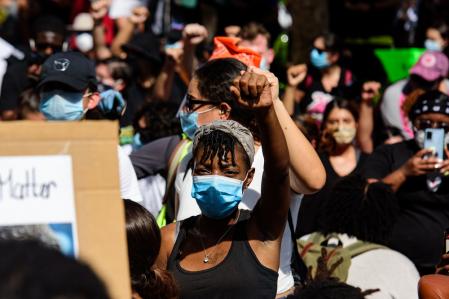 黑色的人戴口罩，并带领一群示威者在迈阿密市中心，佛罗里达州的道路上。