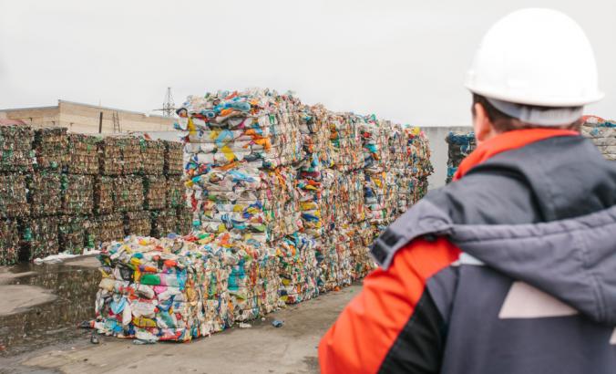 工人在废物加工厂看一堆可回收材料。