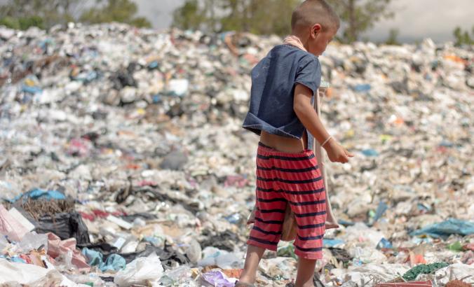一个孩子在垃圾填埋场拾取可回收的废物