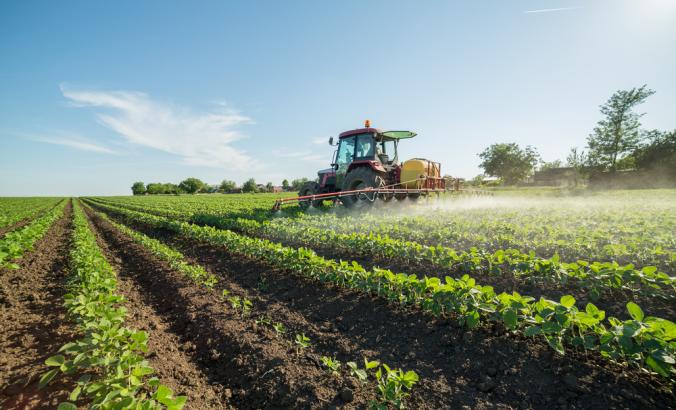 喷洒大豆领域的农夫与杀虫剂和除草剂