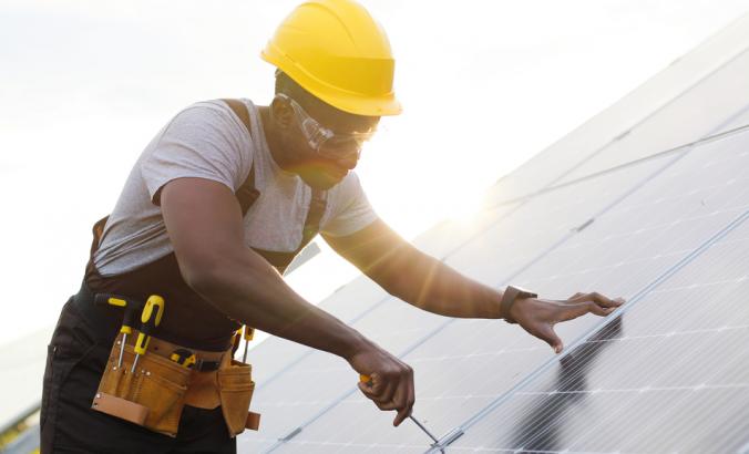 工程师头戴安全帽，身穿制服，在太阳能电站安装太阳能电池板。