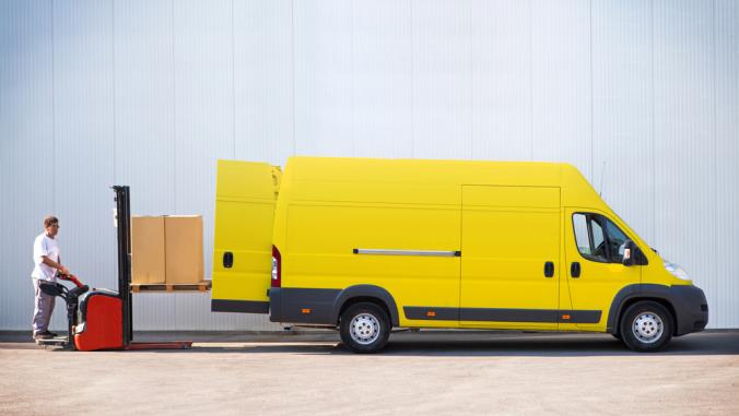 Package delivery, courier is loading a yellow van with parcels.