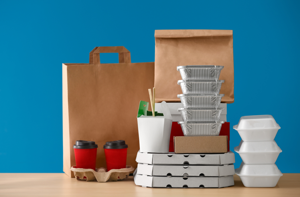 不同类型的食品包装(纸箱、杯子、容器)表在蓝色背景下。
